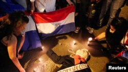 Manifestantes simulan un funeral con un muñeco mientras participan en una protesta contra las políticas de salud del presidente de Paraguay, Mario Abdo Benítez, en Asunción, el 10 de marzo de 2021. de 2021.