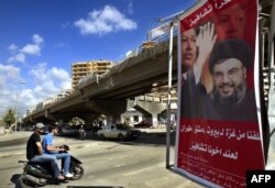 FILE - A poster shows Hassan Nasrallah, the Secretary-General of Hezbollah, and Venezuela's President Hugo Chavez, along with a slogan that reads "Gracias Chavez" is seen hanging from a destroyed bridge at the entrance of southern suburb of Beirut, Sept. 21, 2006.