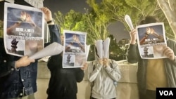 4名中国内地留学生12月10日国际人权日，在香港中文大学校园内举起白纸火炬及标语，呼吁各界关注中国内地“白纸示威”被捕人士，敦促当局尽快放人 (美国之音/汤惠芸)