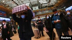 北京火车站里在春运大潮中扛着行李准备乘车返回家乡的旅客。(2023年1月13日)