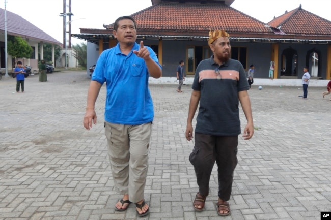 Militan Indonesia Umar Patek (kanan), berjalan bersama teman lamanya Ali Fauzi, mantan militan yang kini menjalankan program deradikalisasi, di Lamongan, Jawa Timur, Indonesia, Selasa, 13 Desember 2022. (AP/Trisnadi)
