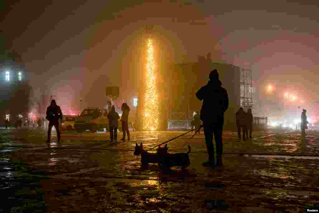 Луѓето поминуваат покрај новогодишна елка за време на густата магла на плоштадот &bdquo;Софија&ldquo; во Киев, среде руската инвазија на Украина.