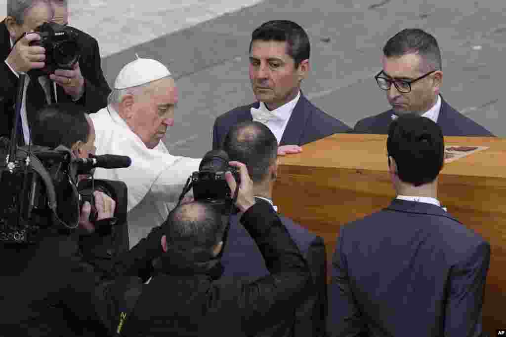 Pope Francis touches the coffin of late Pope Emeritus Benedict before it is carried away after a funeral mass in St. Peter&#39;s Square at the Vatican, Jan. 5, 2023.