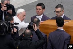 Pope Francis touches the coffin of late Pope Emeritus Benedict XVI before it is carried away after a funeral mass in St. Peter's Square at the Vatican, Jan. 5, 2023.