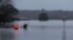 FILE - James Taylor and Joshua Myers paddle kayaks down a flooded residential street on their way to check on a friend's home, after heavy rains inundated the area with floodwaters in the McGraths Hill suburb of Sydney, Australia, July 6, 2022. 