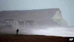 FILE - A person walks on Seaford Beach as Storm Eunice hit Seaford and the south coast of England, Feb. 18, 2022.