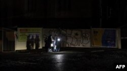 People hold flashlights as they wait at a bus stop during a blackout in Odesa, Ukraine, on Dec. 12, 2022.