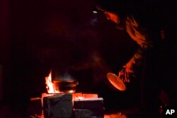 A man cooks food in the yard of an apartment building during a blackout in Kramatorsk, Ukraine, Dec. 16, 2022.