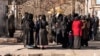 Afghan female university students, stopped by Taliban security personnel, stand next to a university in Kabul, Dec. 21, 2022.