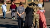 FILE - A female member of the military puts her arms around two female Afghan refugees at a refugee camp in Lakehurst, New Jersey, Sept. 27, 2021. New U.S. government data shows that a record number of Special Immigrant Visas were issued to Afghans in 2023.