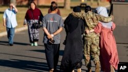 FILE - A female member of the military puts her arms around two female Afghan refugees at an Afghan refugee camp on Joint Base McGuire Dix Lakehurst, N.J., Sept. 27, 2021.