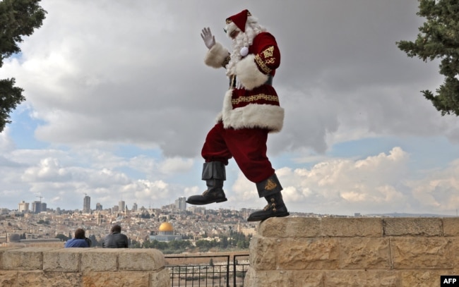 Palestinian Issa Kassissieh, dressed as Santa Claus, prances for a picture on the Mount of Olives in Jerusalem, Dec. 6, 2022.