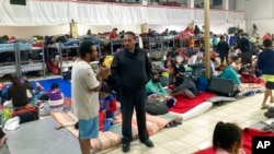 FILE - Gustavo Banda, center-right, pastor of Templo Embajadores de Jesus, Tijuana's largest migrant shelter, speaks with migrants at a shelter, Oct. 13, 2022, in Tijuana, Mexico, along the U.S. border.