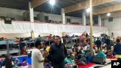 ফাইল ছবি: গুস্তাভো বান্দা(মধ্য-ডানে), টেম্পলো এম্বাজাদোরেস দে জেসাসের যাজক, তিজুয়ানার বৃহত্তম অভিবাসী আশ্রয়স্থল, আমেরিকান সীমান্ত বরাবর, মেক্সিকোর তিজুয়ানাতে একটি আশ্রয়কেন্দ্রে অভিবাসীদের সাথে কথা বলেছেন, ১৩ অক্টোবর, ২০২২ ।