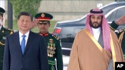 In this image taken from footage by Saudi State TV, Chinese President Xi Jinping, listens to the Chinese national anthem next to Saudi Crown Prince and Prime Minister Mohammed bin Salman in Riyadh, Saudi Arabia, Dec. 8, 2022.