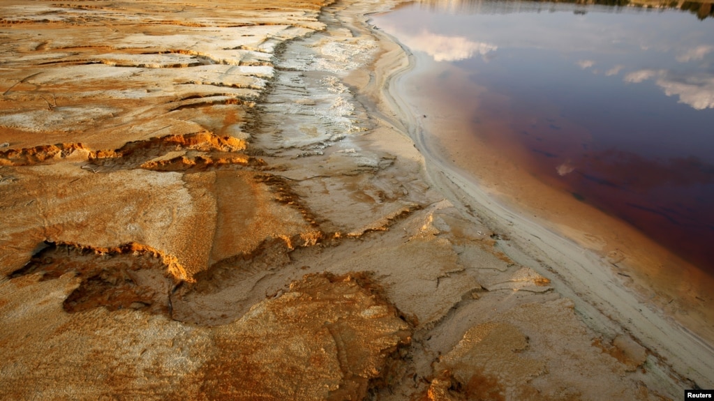 FILE - Polluted water emanating from mining operations fills a dam near Johannesburg, South Africa, Sept. 24, 2015. 