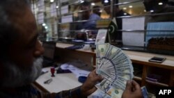En esta imagen tomada el 10 de enero de 2023, un comerciante cuenta dólares estadounidenses en un mercado de cambio de dinero en Karachi, Pakistán.