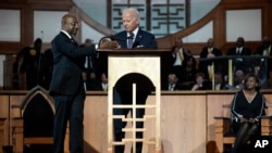 El senador Raphael Warnock, demócrata por Georgia., pastor principal de la Iglesia Bautista Ebenezer, ayuda al presidente Joe Biden con el micrófono en la Iglesia Bautista Ebenezer en Atlanta, el 15 de enero de 2023, durante un servicio en honor a Martin Luther King Jr.