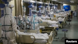 FILE - Medical workers in protective suits attend to COVID-19 patients at the intensive care unit of a designated hospital during the COVID-19 outbreak in Wuhan, China, Feb. 6, 2020. (China Daily via Reuters) 