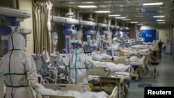 FILE - Medical workers in protective suits attend to COVID-19 patients at the intensive care unit of a designated hospital during the COVID-19 outbreak in Wuhan, China, Feb. 6, 2020. (China Daily via Reuters/File Photo) 