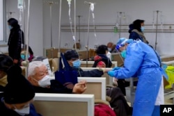 En esta foto publicada por la Agencia de Noticias Xinhua, un trabajador médico ayuda a un paciente con un goteo intravenoso en una institución de atención médica comunitaria en Shanghái, China, el 5 de enero de 2023.
