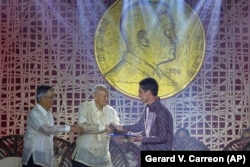 Gary Bencheghib menerima penghargaannya dari Aurelio Montinola, kiri, dan Ramon Magsaysay Jr., tengah, pada upacara Penghargaan Ramon Magsaysay di Manila pada Rabu, 30 November 2022. (Foto: AP/Gerard V. Carreon)