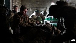 Tentara Ukraina memberikan pertolongan pertama kepada seorang rekannya yang terluka dalam pertempuran dengan pasukan Rusia di wilayah Donetsk, Ukraina (foto: dok). Banyak relawan asing ikut bertempur di Ukraina. 