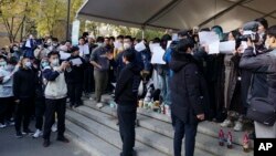 北京清華大學的學生手舉白紙抗議嚴厲的防疫政策，悼念日前在新疆烏魯木齊市死於火災的至少10名遇難者。 （2022年11月27日）