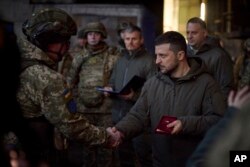 Ukrainian President Volodymyr Zelenskyy, right, awards a serviceman at the site of the heaviest battles with the Russian invaders in Bakhmut, Ukraine, Dec. 20, 2022, in this photo provided by the Ukrainian Presidential Press Office.