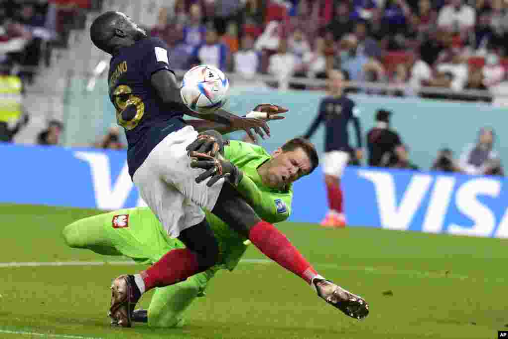 France&#39;s Dayot Upamecano, left, and Poland&#39;s goalkeeper Wojciech Szczesny, right, collide during the World Cup round of 16 soccer match between France and Poland, at the Al Thumama Stadium in Doha, Qatar.