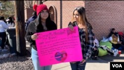 Las hermanas Jaqueline y Geraldine Guerrero sostienen un cartel donde le dan la bienvenida al presidente Joe Biden a El Paso y le piden ayuda para venezolanos, cubanos, nicaragüenses y haitianos, en El Paso, Texas, el 8 de enero de 2023.