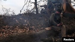 Volodymyr, the commander of a self-propelled artillery vehicle with the 24th Mechanized Brigade of King Danylo of the Ukrainian Army keeps warm by a fire to stave off the bitter cold, near Bakhmut, Dec. 3, 2022.