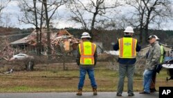 Workers look on as crews restore power in Farmerville, La., Dec. 14, 2022, after a destructive storm system swept through the area.