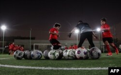 Ali Koteich, direktur Akademi Olahraga Cedars, mengawasi pelatihan anak-anak di lapangan sepak bola di fasilitas di ibu kota Qatar, Doha, 8 November 2022. (KARIM JAAFAR/AFP)