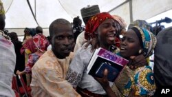 FILE - A girl who was kidnapped by Boko Haram extremists celebrates with family members after her release with others, during a church service held in Abuja, Nigeria, on Oct. 16, 2016.