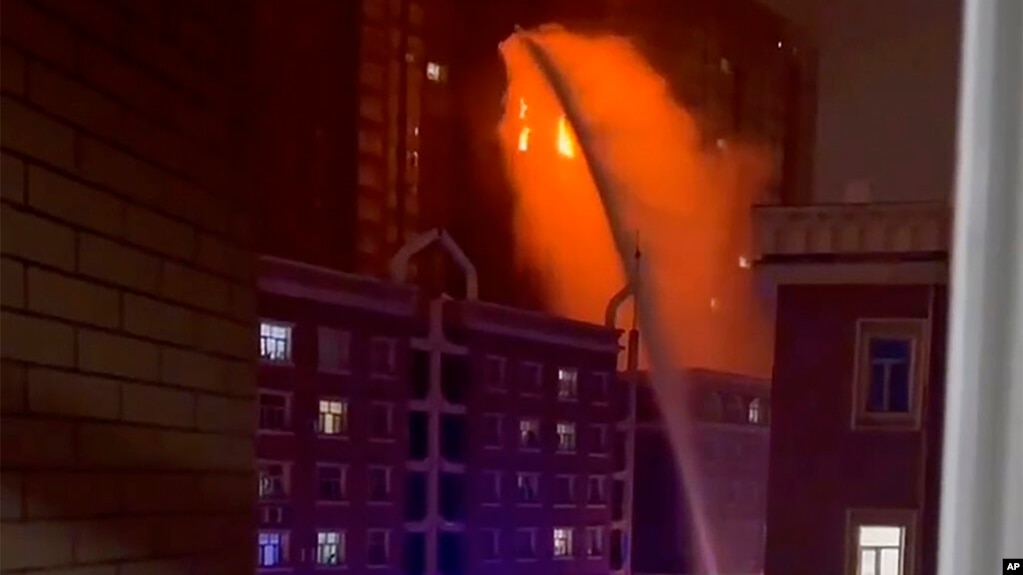 视频截图显示，乌鲁木齐消防人员向发生大火的住宅楼喷水灭火。(photo:VOA)