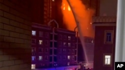 In this image from video, crews spray water on a fire at a residential building in Urumqi in western China's Xinjiang Uyghur Autonomous Region, Nov. 24, 2022. It was the country's second major fire accident this week.