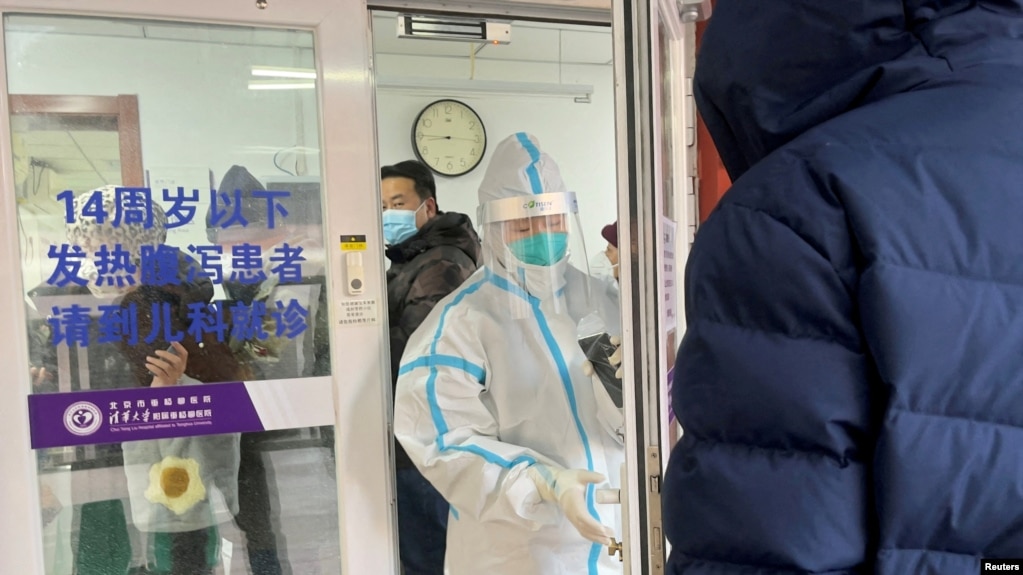 2022年12月15日，一名男子在北京一家医院的发热门诊门外排队等待。一位身着防护服的医务人员正准备关门。中国有关当局毫无预兆地宣布解封后，新冠肺炎的感染人数和死亡人数不断增加，引起人们的恐慌。(photo:VOA)