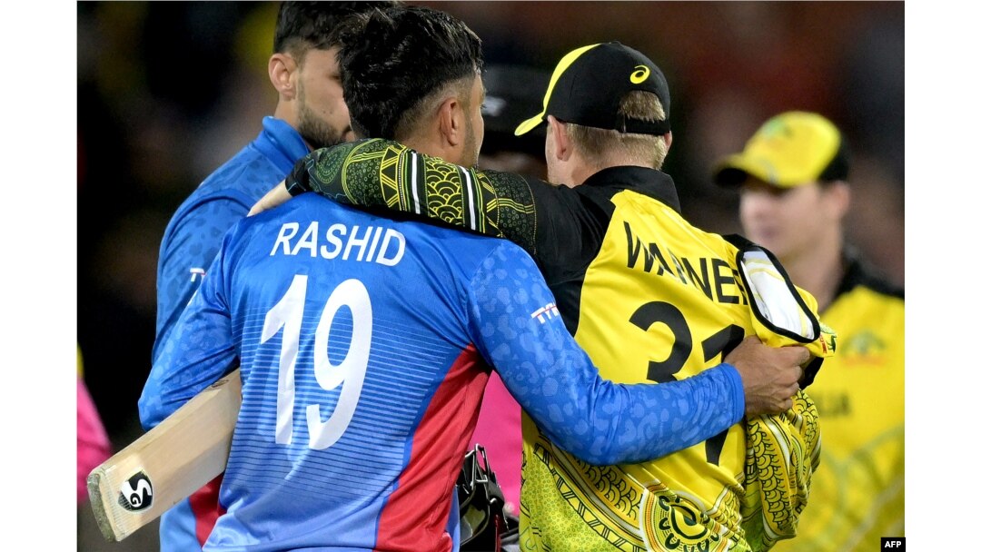 David Warner (kanan) dari Australia merangkul Rashid Khan dari Afghanistan setelah pertandingan kriket putra Piala Dunia ICC 2022 antara Australia dan Afghanistan di Adelaide Oval di Adelaide, 4 November 2022. (Brenton EDWARDS / AFP)