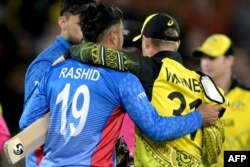 David Warner (kanan) dari Australia merangkul Rashid Khan dari Afghanistan setelah pertandingan kriket putra Piala Dunia ICC 2022 antara Australia dan Afghanistan di Adelaide Oval di Adelaide, 4 November 2022. (Brenton EDWARDS / AFP)