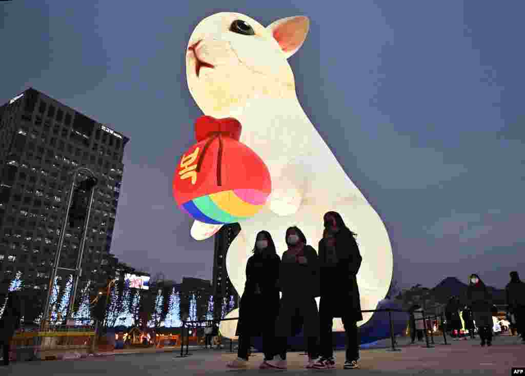 People walk past a brightly lit lantern for the upcoming Year of the Rabbit during Seoul Lantern Festival at Gwanghwamun square in Seoul, South Korea.
