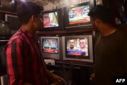 FILE - People watch a news television broadcast of the nomination of Pakistan's next army chief, General Asim Munir, at a market in Karachi, Nov. 24, 2022.