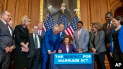 House Speaker Nancy Pelosi, accompanied by Senate Majority Leader Sen. Chuck Schumer to her left and other members of Congress, signs the H.R. 8404, the Respect For Marriage Act, on Capitol Hill in Washington, Dec. 8, 2022.