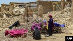 Masyarakat Afghanistan menjemur pakaian mereka di semak-semak kering dekat reruntuhan rumah yang rusak akibat gempa bumi di distrik Bermal, Provinsi Paktika, pada 23 Juni 2022. (Foto: AFP)