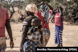 Women make up about half the gold miners in Senegal and often carry their children with them. Here, women work at a gold mine in the country's Kedougou region Nov. 16, 2022.