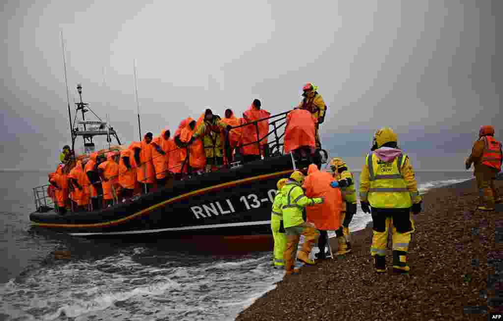 Migrants, picked up at sea attempting to cross the English Channel, are helped ashore from a Royal National Lifeboat Institution lifeboat, at Dungeness on the southeast coast of England.