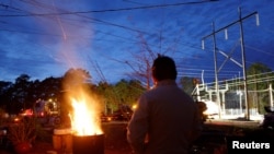 Người dân North Carolina đang sưởi ấm bên đống lửa trong khi các công nhân điện lực của Duke Energy đang cố gắng khôi phục lưới điện ở Carthage hôm 4/12 năm 2022. 
