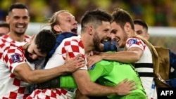 Penyerang Kroasia Bruno Petkovic (#16), penjaga gawang Kroasia Dominik Livakovic dan rekan setimnya merayakan kemenangan atas Brazil dan memastikan lolos ke babak semifinal Piala Dunia.
