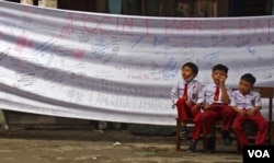 Siswa SDN Pondok Cina 1, Depok bermain di depan spanduk penolakan terhadap penggusuran sekolah mereka oleh Pemerintah Kota Depok. Menurut rencana Pemkot, di lahan SDN Pocin 1 akan dibangun sebuah masjid raya. (VOA/Indra Yoga)