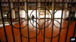 FILE - A man walks past a fence with Olympic Rings near the Russian National Olympic Committee building in Moscow, Russia, Dec. 17, 2020. 